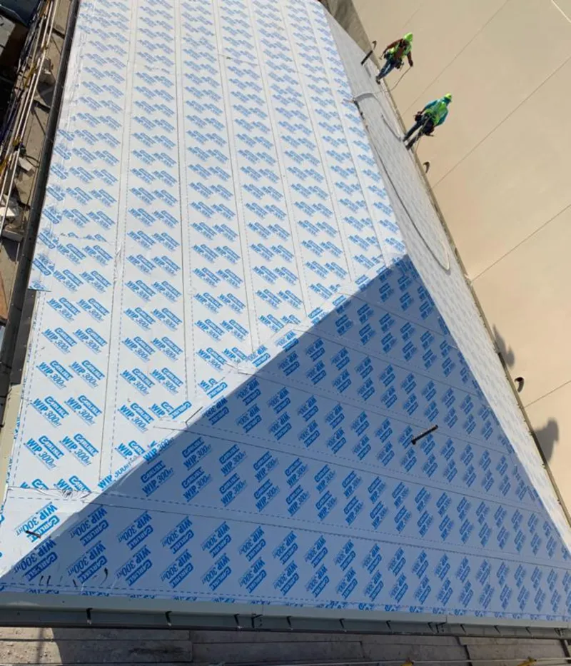 Professional roofers installing underlayment on a metal roof in Woodburn